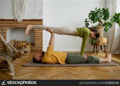 Young couple training yoga in pair doing acrobatic plank together. Millennial man and woman making balancing exercise. Young couple training yoga in pair doing acrobatic plank together