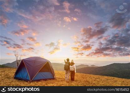 Young couple traveler looking landscape at sunset and c&ing on mountain, Adventure travel lifestyle concept