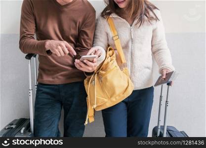 Young couple traveler with baggage and backpack using smartphone at the airport