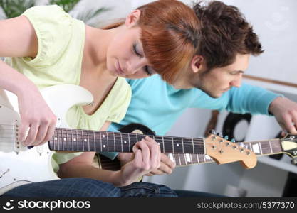 Young couple tuning and playing guitar