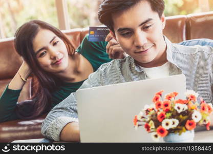 Young couple use credit card for online shopping on internet website at home. Number on the credit card is mock up. No personal information shown on the credit card. Online business shopping concept.