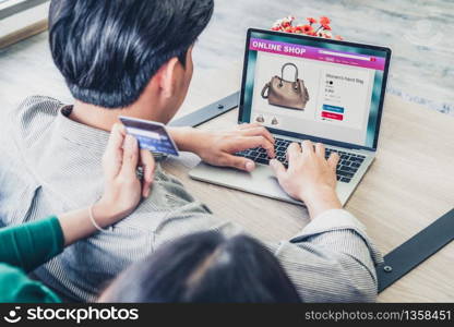 Young couple use credit card for online shopping on internet website at home. Number on the credit card is mock up. No personal information shown on the credit card. Online business shopping concept.