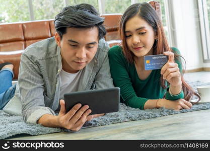 Young couple use credit card for online shopping on internet website at home. Number on the credit card is mock up. No personal information shown on the credit card. Online business shopping concept.