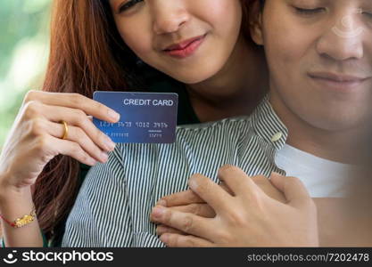 Young couple use credit card for online shopping on internet website at home. Number on the credit card is mock up. No personal information shown on the credit card. Online business shopping concept.