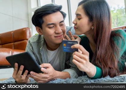 Young couple use credit card for online shopping on internet website at home. Number on the credit card is mock up. No personal information shown on the credit card. Online business shopping concept.