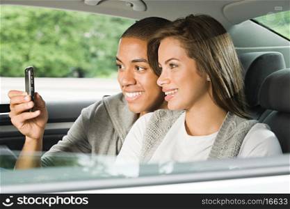 Young couple using a cellular phone in car
