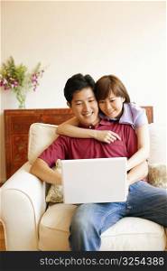 Young couple using a laptop and smiling