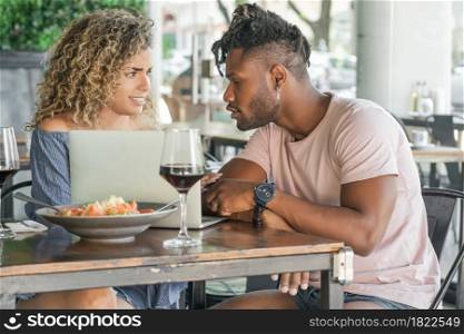 Young couple using a laptop while having lunch together at a restaurant.