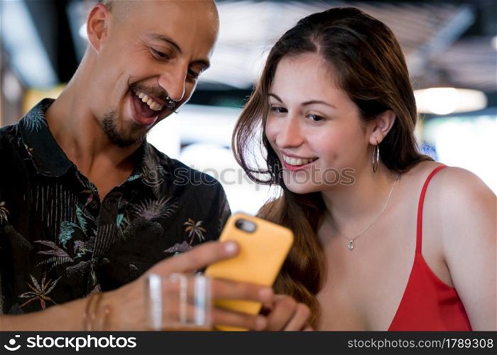 Young couple using a mobile phone while enjoying a date together at a restaurant.