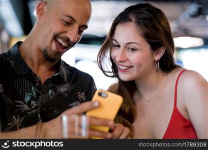 Young couple using a mobile phone while enjoying a date together at a restaurant.