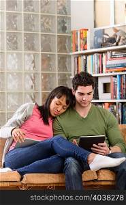 Young couple using digital tablets in living room