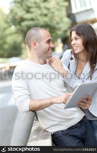 Young couple using electronic tablet in town