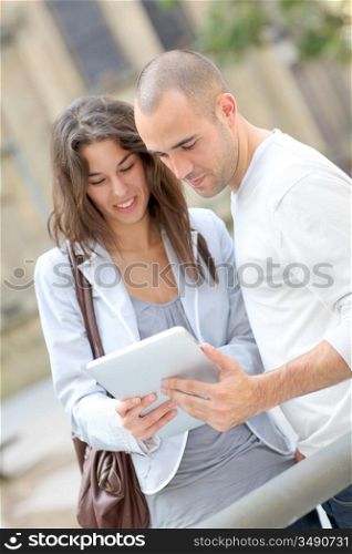 Young couple using electronic tablet in town