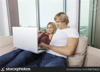 Young couple using laptop in living room at home