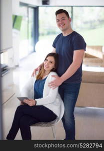 Young couple using tablet computer at luxury home together, looking at screen, smiling.