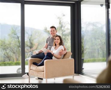 Young couple using tablet computer at luxury home together, looking at screen, smiling.