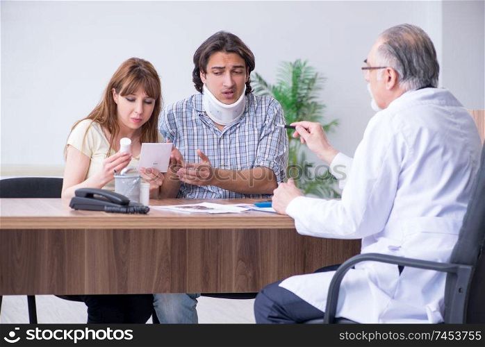 Young couple visiting old male doctor 
