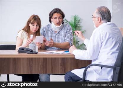 Young couple visiting old male doctor 