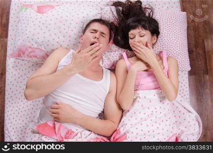Young couple waking up and yawning in bed