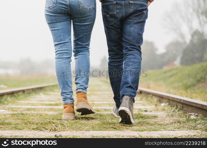 young couple walking along tracks together