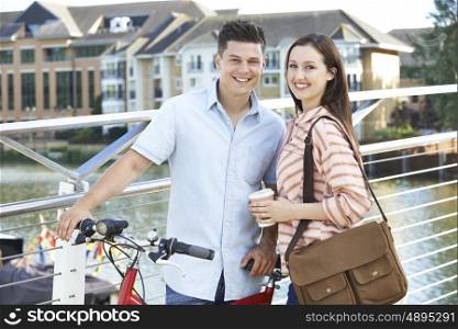 Young Couple Walking And Cycling To Work In Urban Setting