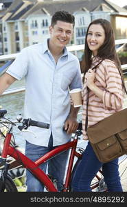 Young Couple Walking And Cycling To Work In Urban Setting