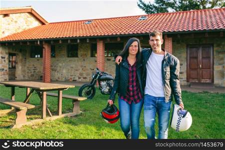 Young couple walking embraced outdoors with custom motorcycle in the background. Couple walking embraced and custom motorcycle