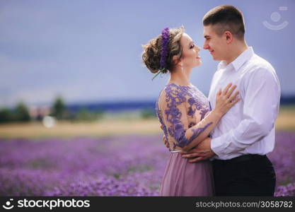 Young couple walking in a lavender field. girl in a luxurious purple dress. beautiful couple in a flowering field.. Young couple walking in a lavender field. girl in a luxurious purple dress. beautiful couple in a flowering field