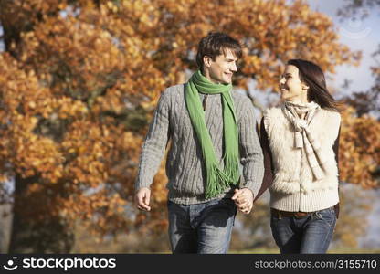 Young Couple Walking In Park Holding Hands