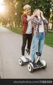 Young couple walking on gyro board in summer park. Outdoor recreation with electric gyroboard. Transport with balance technology