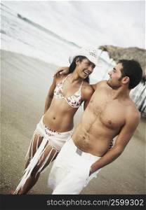 Young couple walking on the beach and smiling