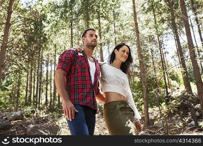 Young couple walking through forest, arm around