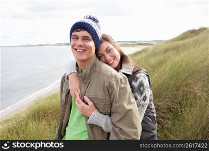 Young Couple Walking Through Sand Dunes Wearing Warm Clothing