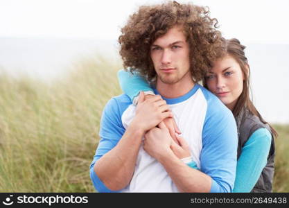 Young Couple Walking Through Sand Dunes Wearing Warm Clothing