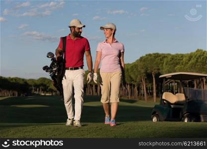 young couple walking to next hole on golf course. man carrying golf bag
