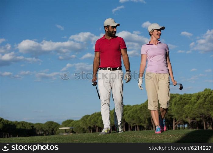 young couple walking to next hole on golf course. man carrying golf bag