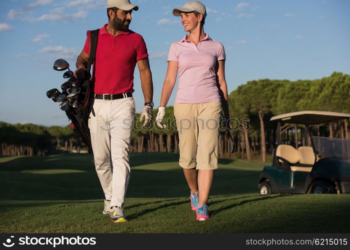 young couple walking to next hole on golf course. man carrying golf bag