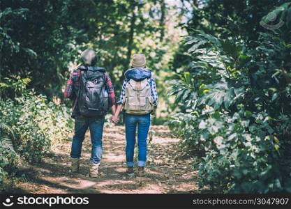 Young couple walking with backpacks in forest. Adventure hikes