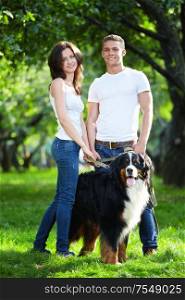 Young couple walking with dog in park