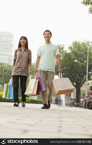 Young couple walking with shopping bags in hands, Beijing, China