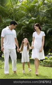 Young couple walking with their daughter in a garden