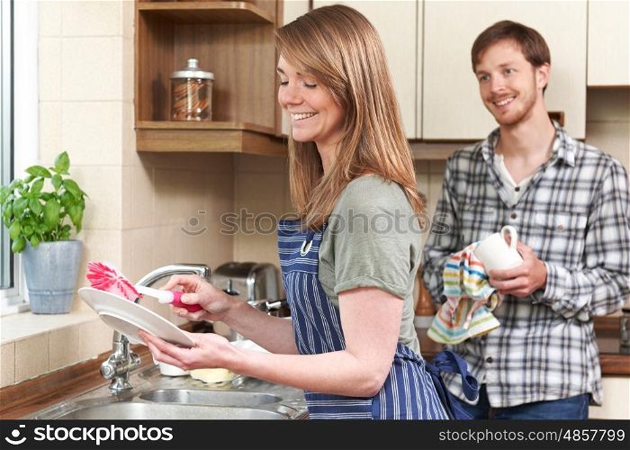 Young Couple Washing Up At Sink Together