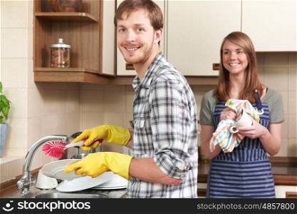 Young Couple Washing Up At Sink Together