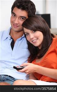 Young couple watching TV with a remote control