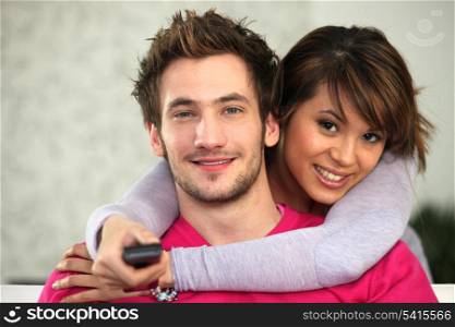 Young couple watching TV with a remote control
