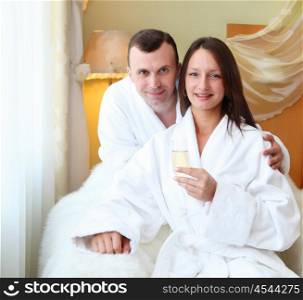 young couple wearing bathrobes with glasses of champagne