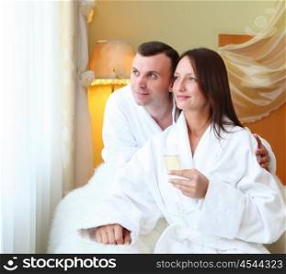 young couple wearing bathrobes with glasses of champagne