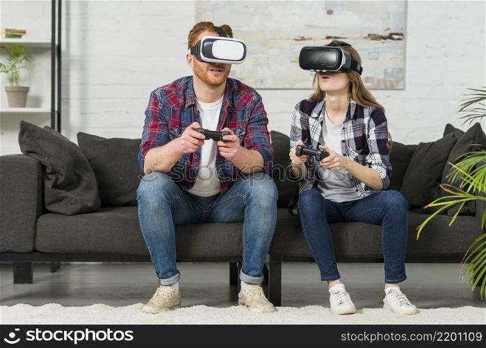 young couple wearing virtual reality goggles playing video game living room
