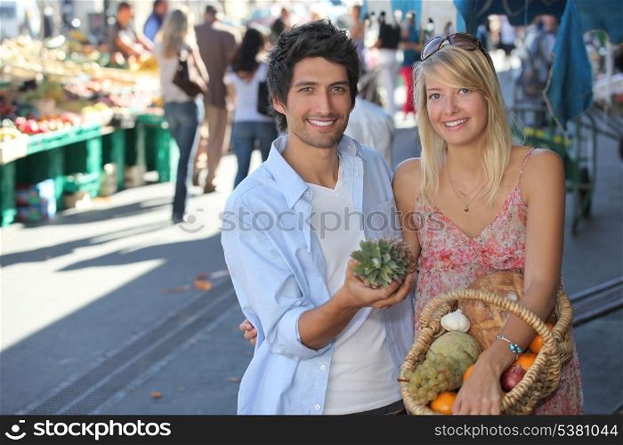 Young couple with a basket of fruit in a busy marketplace