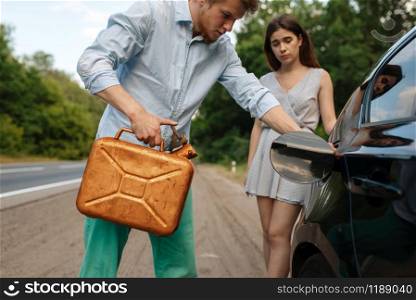 Young couple with a canister of gasoline, out of gas, car breakdown. Broken automobile or emergency accident with vehicle, trouble with punctured auto tire on highway